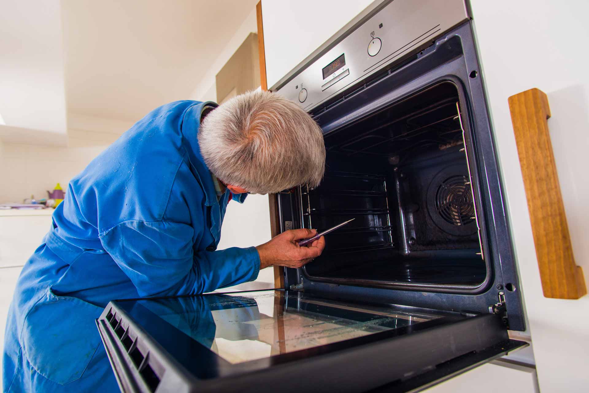 Appliance repair technician working on wall oven